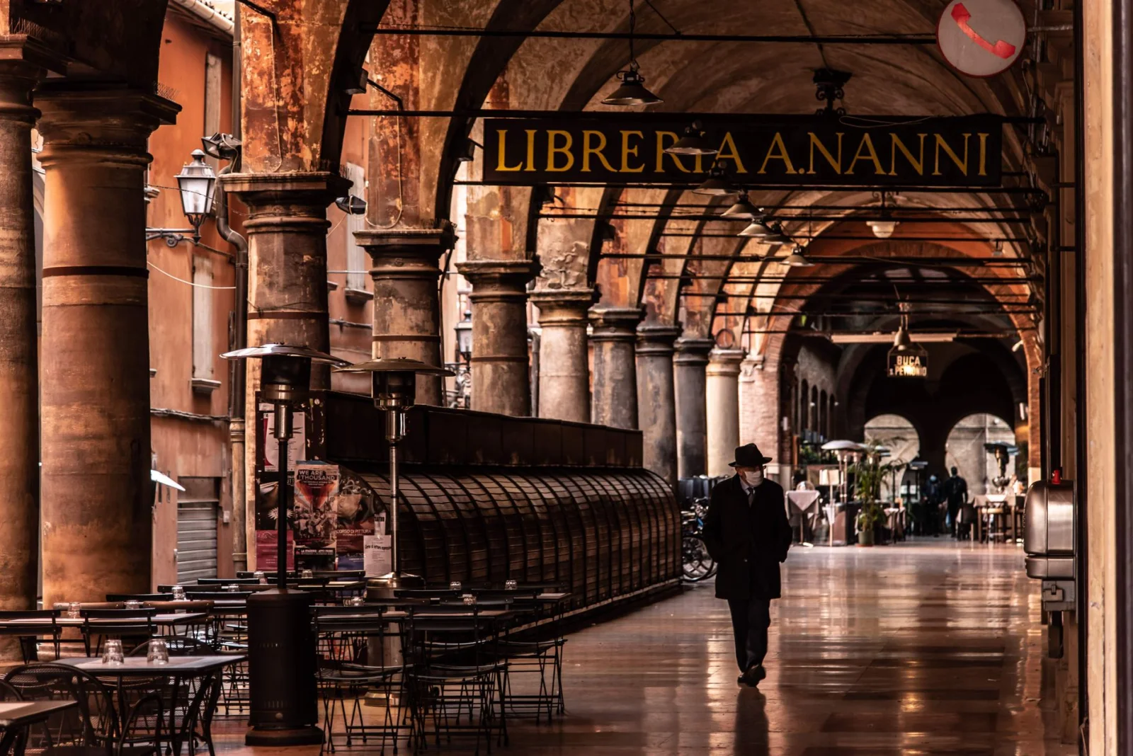 Pedestrians walking beneath Bologna's historic porticoes