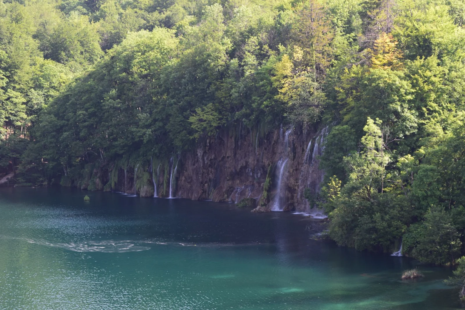 A tranquil landscape with waterfalls at Plitvice Lakes National Park, Croatia, surrounded by lush greenery.