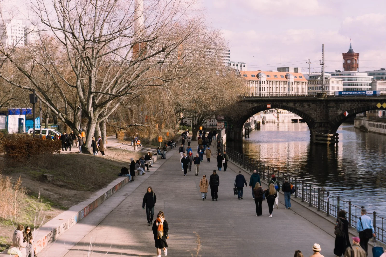 People strolling along a riverside path in a historic European city